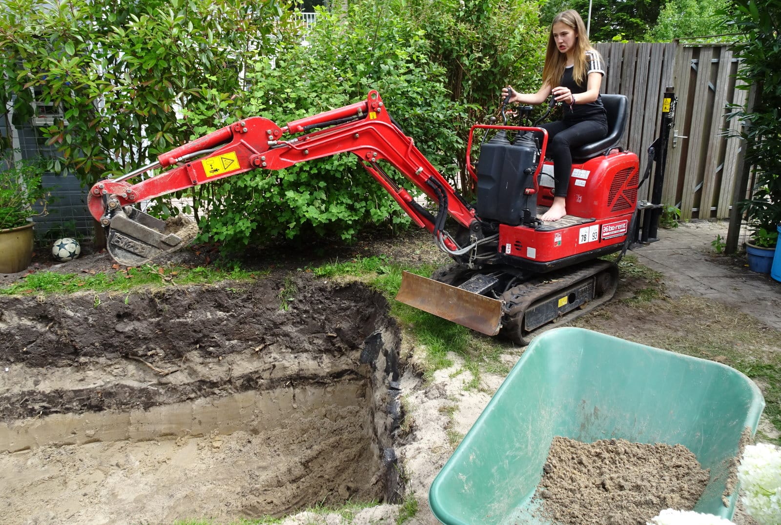 Gat-in-tuin-graven-voor-zwembad-met-graafmachine